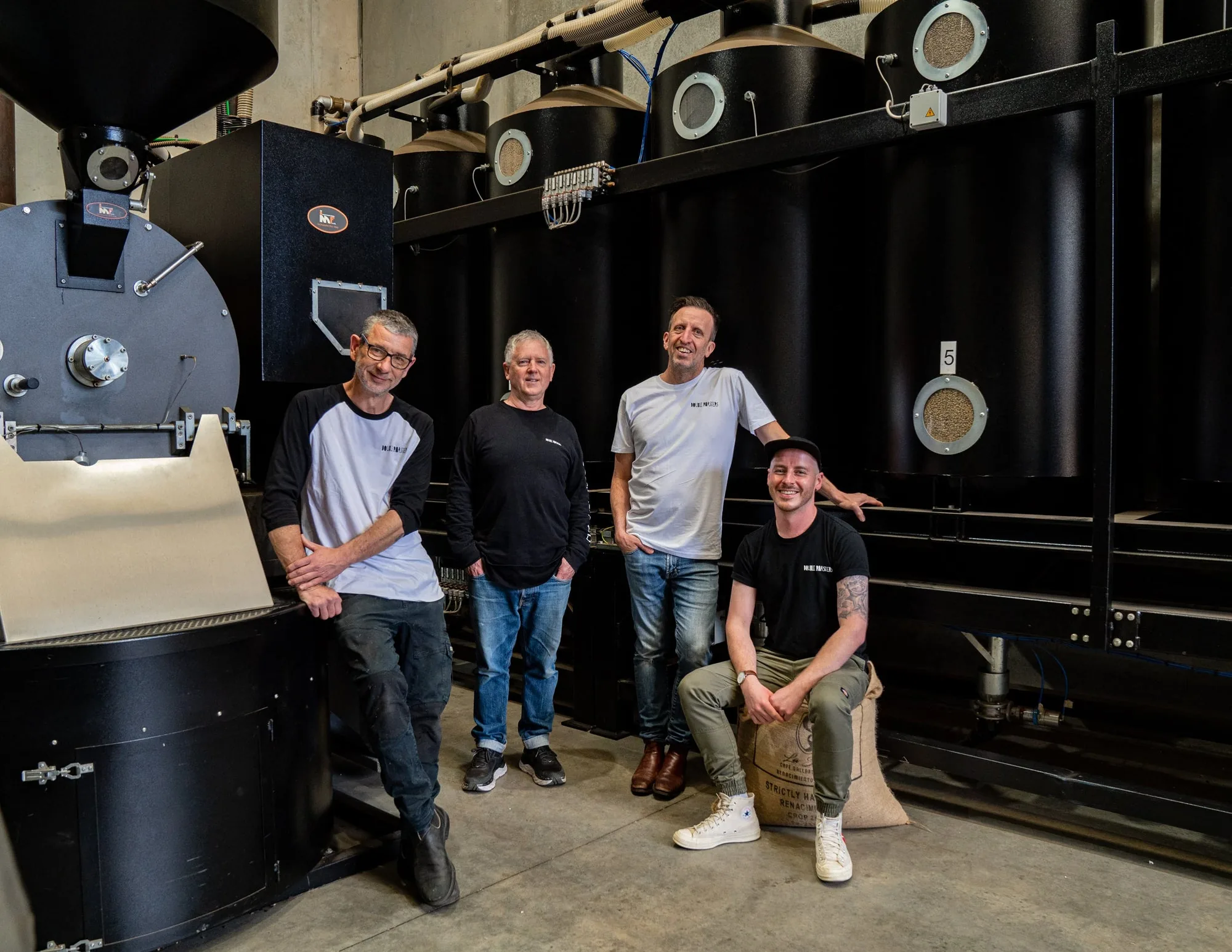The Double Roasters team beside their roaster and green coffee silos in Marrickville